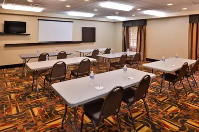 a conference room with tables and chairs and a screen at Wingate by Wyndham Steubenville in Steubenville