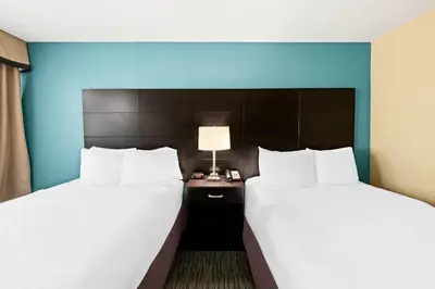 two beds in a hotel room with blue walls at Quality Inn Dayton Airport in Englewood