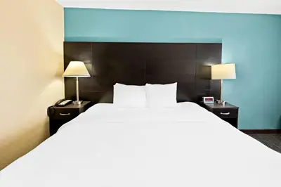 a large bed in a hotel room with two lamps at Quality Inn Dayton Airport in Englewood