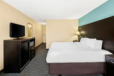 a hotel room with a bed and a flat screen tv at Quality Inn Dayton Airport in Englewood