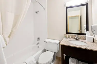 a bathroom with a toilet and a sink and a mirror at Quality Inn Dayton Airport in Englewood