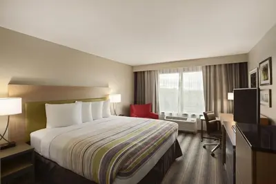 a hotel room with a large bed and a red chair at Country Inn & Suites by Radisson, Sandusky South, OH in Milan