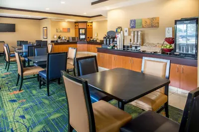 a restaurant with tables and chairs and a bar at Fairfield Inn & Suites Canton in North Canton