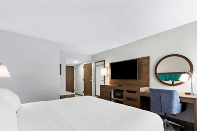 a hotel room with a bed and a desk and a mirror at Hampton Inn Washington in Washington