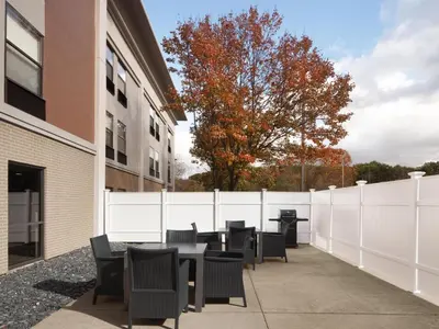 a patio with tables and chairs next to a white fence at Hampton Inn Youngstown/Boardman in Poland