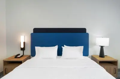 a bed with a blue headboard and two night stands at Hampton Inn Marietta in Marietta