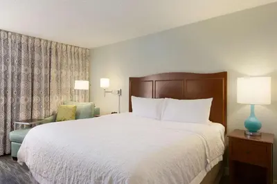 a hotel room with a large bed and a chair at Hampton Inn Zanesville in Zanesville