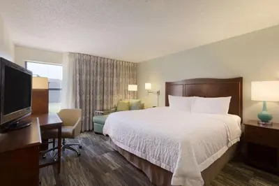 a hotel room with a bed and a desk and a television at Hampton Inn Zanesville in Zanesville