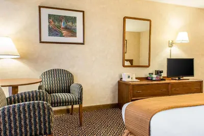 a hotel room with a bed and a chair and a mirror at Quality Inn and Conference Center in Springfield