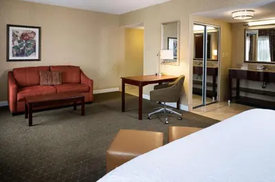 a hotel room with a bed and a couch and a desk at Hampton Inn & Suites Toledo-Perrysburg in Rossford