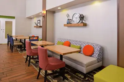 a restaurant with tables and a couch and chairs at Hampton Inn & Suites Wilmington in Wilmington