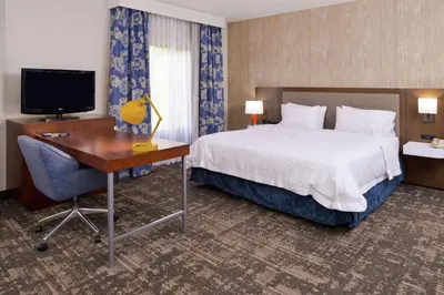 a hotel room with a bed and a desk and a television at Hampton Inn & Suites Wilmington in Wilmington