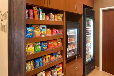 a book shelf filled with lots of food next to a refrigerator at Fairfield Inn & Suites by Marriott Dayton South in Centerville