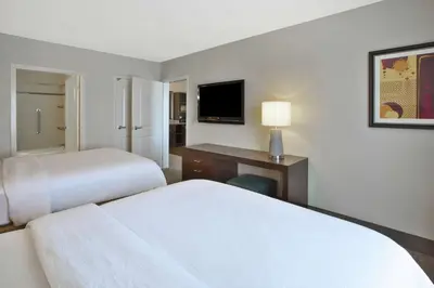 a hotel room with two beds and a desk with a television at Embassy Suites Columbus - Airport in Columbus
