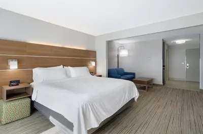 a hotel room with a large bed and a blue chair at Holiday Inn Express Hotel & Suites Weston by IHG in Weston