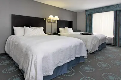 a hotel room with two beds with white sheets at Hampton Inn Defiance in Defiance