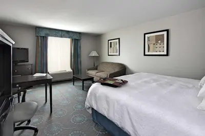 a hotel room with a bed and a couch and a desk at Hampton Inn Defiance in Defiance