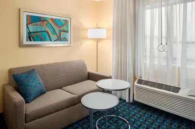 a living room with a couch and tables in a hotel room at Fairfield Inn & Suites Lima in Lima