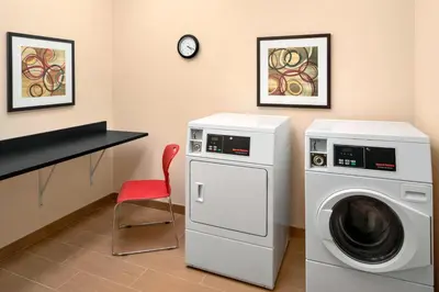 a laundry room with a washing machine and a red chair at Fairfield Inn & Suites Lima in Lima