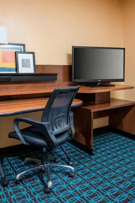 a desk with a chair in front of a television at Fairfield Inn & Suites Ashland in Ashland