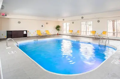 a large swimming pool in a room with yellow chairs at Fairfield Inn & Suites Ashland in Ashland