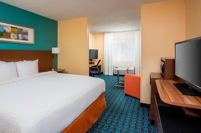 a hotel room with a bed and a flat screen tv at Fairfield Inn & Suites Ashland in Ashland