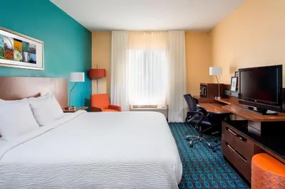 a hotel room with a bed and a flat screen tv at Fairfield Inn & Suites Ashland in Ashland
