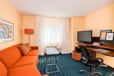 a hotel room with an orange couch and a desk at Fairfield Inn & Suites Mansfield Ontario in Mansfield