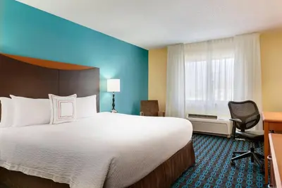 a hotel room with a large bed and a desk at Fairfield Inn & Suites by Marriott Toledo Maumee in Maumee