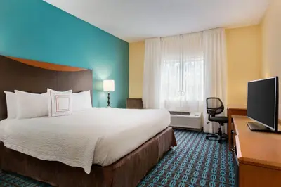 a hotel room with a bed and a flat screen tv at Fairfield Inn & Suites by Marriott Toledo Maumee in Maumee