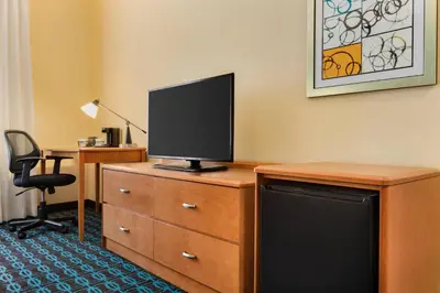 a room with a desk with a television on a dresser at Fairfield Inn & Suites by Marriott Toledo Maumee in Maumee
