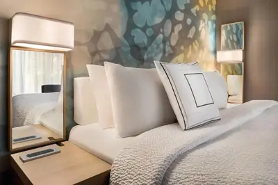 a bed with white pillows and a mirror next to it at Courtyard by Marriott Dayton North in Dayton