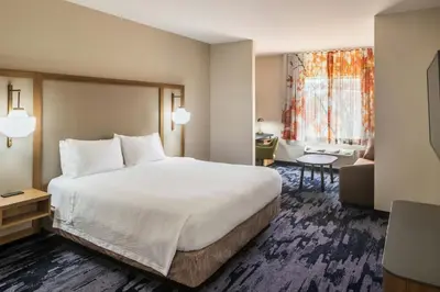 a bedroom with a large bed and a living room at Fairfield Inn by Marriott Richmond in New Paris