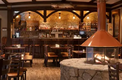 a restaurant with a bar with tables and a fireplace at Stonewall Resort in Roanoke