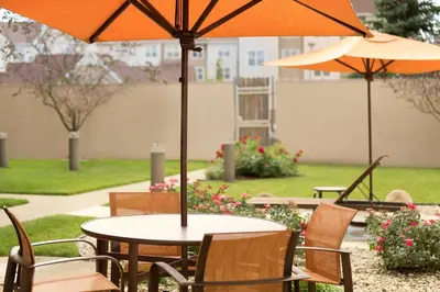 a table and chairs with umbrellas on a patio at Courtyard by Marriott Dayton Beavercreek in Beavercreek