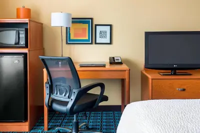 a room with a desk and a chair and a television at Fairfield Inn Muncie in Muncie