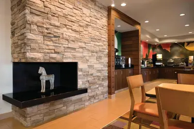a stone fireplace in a restaurant with a table and chairs at Fairfield Inn Muncie in Muncie
