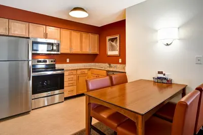 a kitchen with a wooden table and stainless steel appliances at Residence Inn by Marriott Dayton Beavercreek in Beavercreek