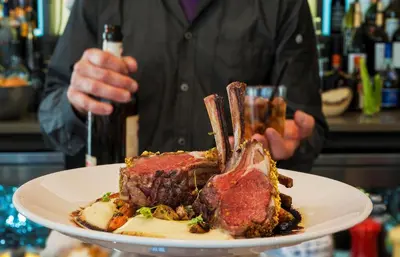 a person holding a plate with a piece of meat at The Hotel at Oberlin in Oberlin
