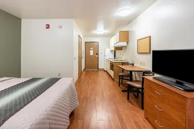 a bedroom with a bed and a desk and a kitchen at HomeTowne Studios by Red Roof Columbus in Columbus