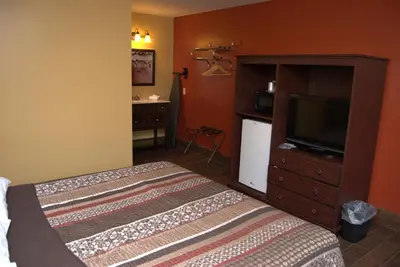 a bedroom with a bed and a dresser with a television at Commodore Resort in Put-in-Bay