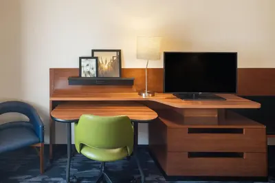 a desk with a computer monitor and a green chair at Fairfield Inn & Suites by Marriott Chillicothe in Chillicothe