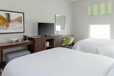 a hotel room with two beds and a desk with a television at Hampton Inn & Suites Columbus Scioto Downs in Columbus