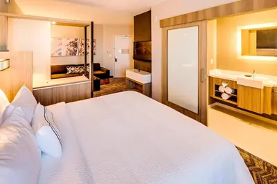 a bedroom with a large white bed and a bathroom at SpringHill Suites by Marriott Dayton Vandalia in Murlin Heights