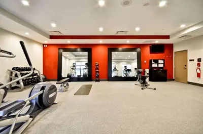 a gym with cardio equipment and orange walls at Homewood Suites by Hilton Cincinnati/West Chester in West Chester