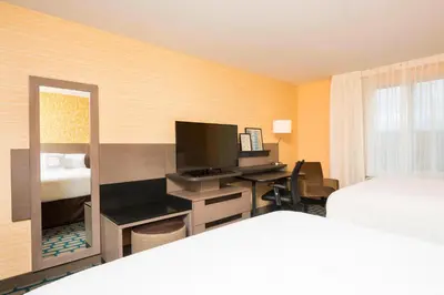 a hotel room with a desk with a television and a bed at Fairfield Inn & Suites by Marriott Medina in Medina