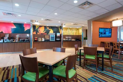 a dining room with tables and chairs and a bar at Fairfield Inn & Suites by Marriott Medina in Medina