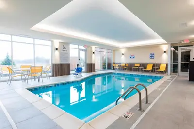 a pool in a hotel with chairs and a table at Fairfield Inn & Suites by Marriott Medina in Medina