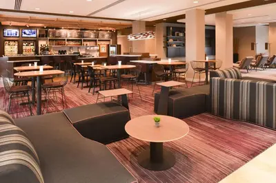 a restaurant with tables and chairs and a bar at Courtyard by Marriott Toledo North in Toledo