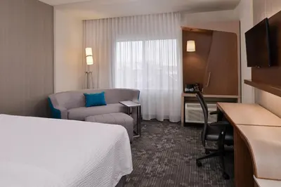 a hotel room with a bed and a chair and a desk at Courtyard by Marriott Toledo North in Toledo